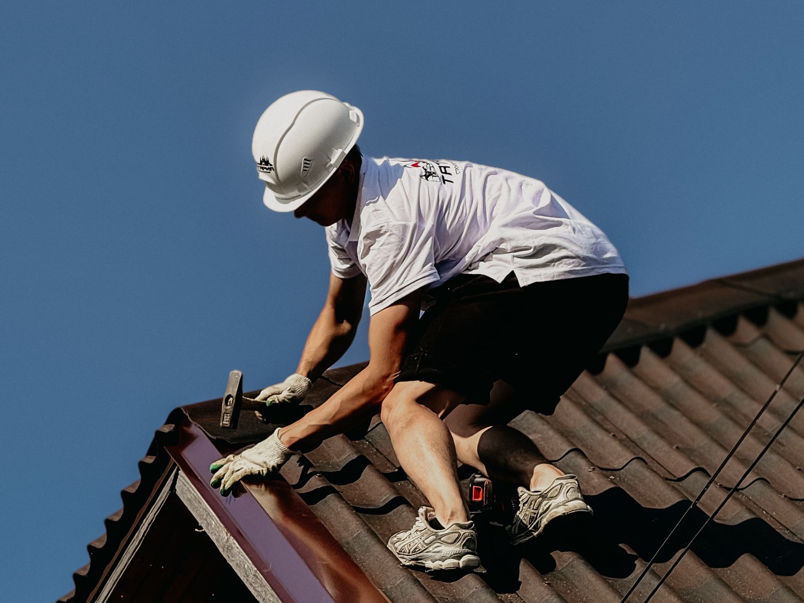 Couvreur professionnel travaillant en sécurité sur une toiture en tuile